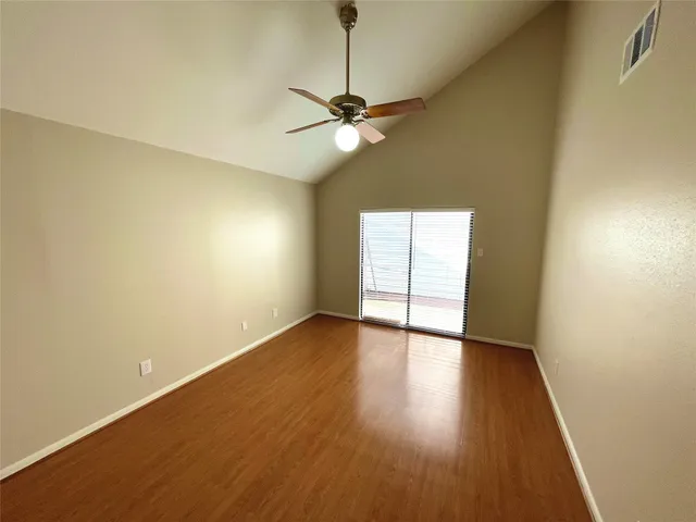 a view of an empty room with window and wooden floor