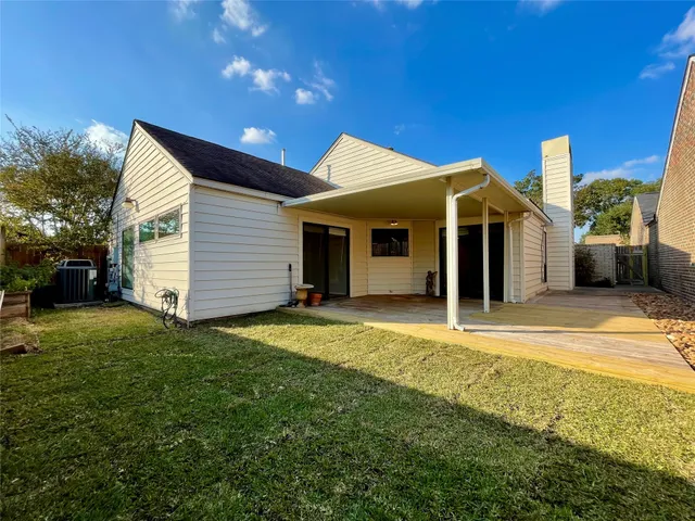 a view of a white house with a yard potted plants and a table and chairs