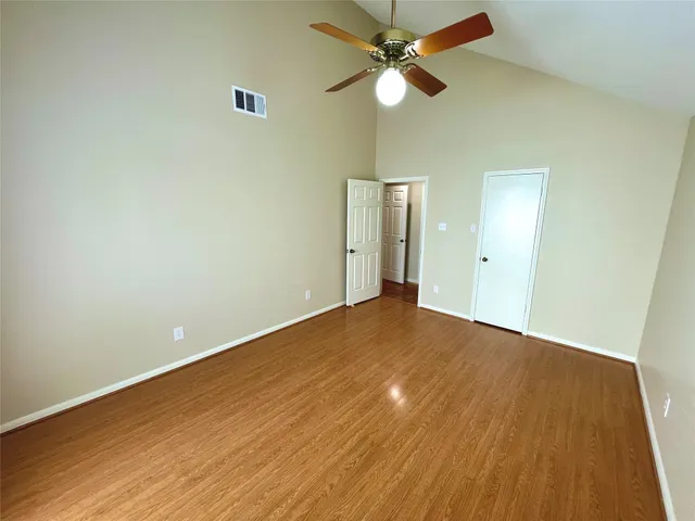 an empty room with a ceiling fan and wooden floor