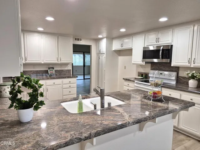 a kitchen with stainless steel appliances granite countertop a sink a stove and a granite counter tops