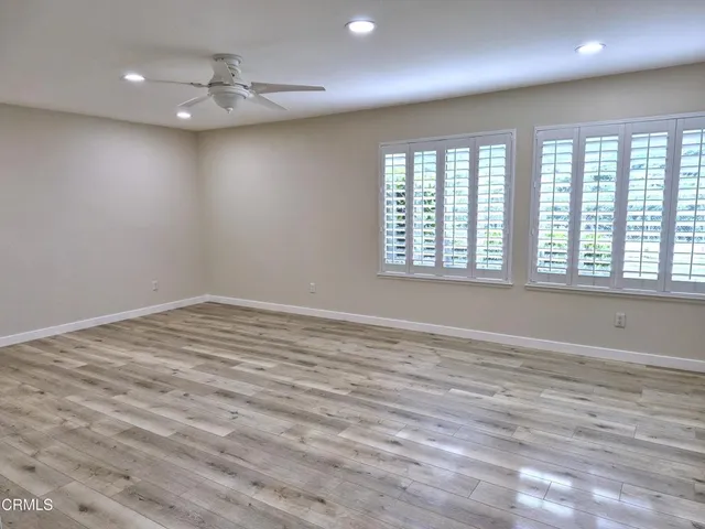 an empty room with wooden floor and windows