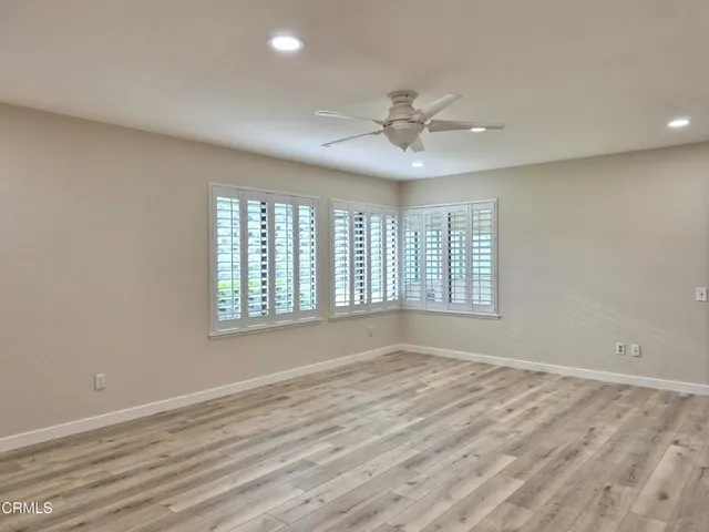 a view of an empty room with a window and wooden floor