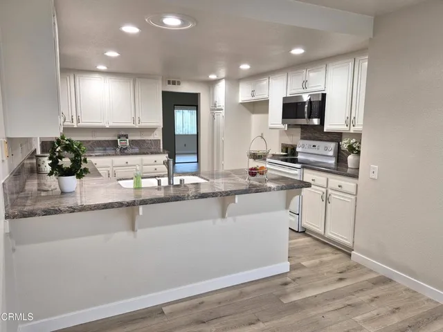 a kitchen with stainless steel appliances granite countertop a sink a stove and cabinets