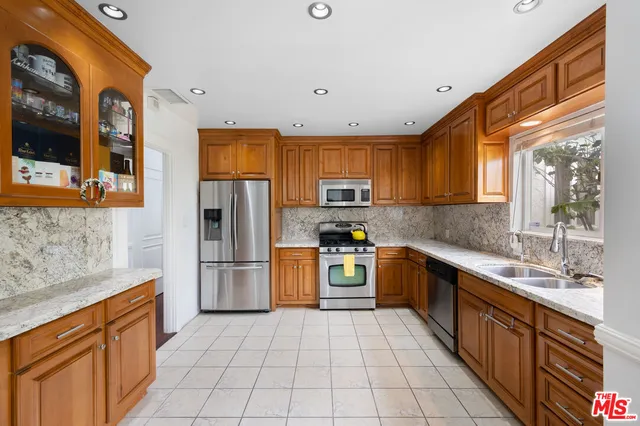 a kitchen with stainless steel appliances granite countertop a refrigerator and a stove top oven