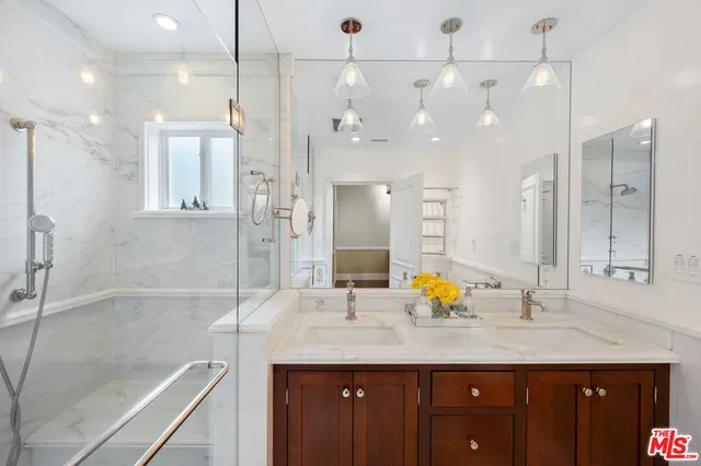 a bathroom with a granite countertop sink a large mirror and shower