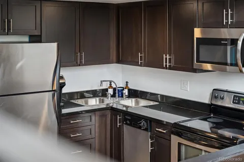 a kitchen with granite countertop a refrigerator stove and sink