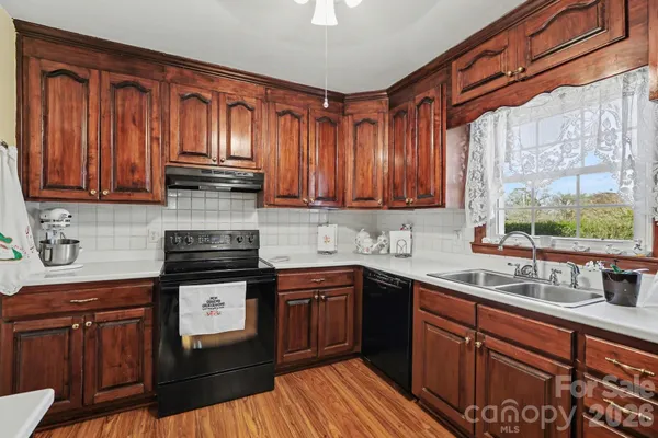 a kitchen with stainless steel appliances granite countertop wooden cabinets a sink and dishwasher with wooden floor