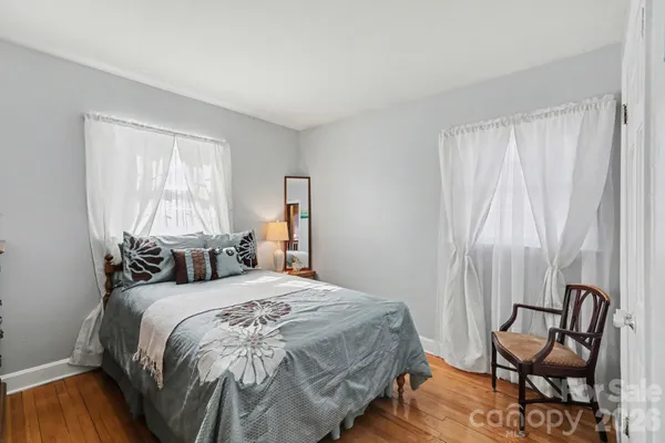 a bedroom with a bed a chair and next to a window