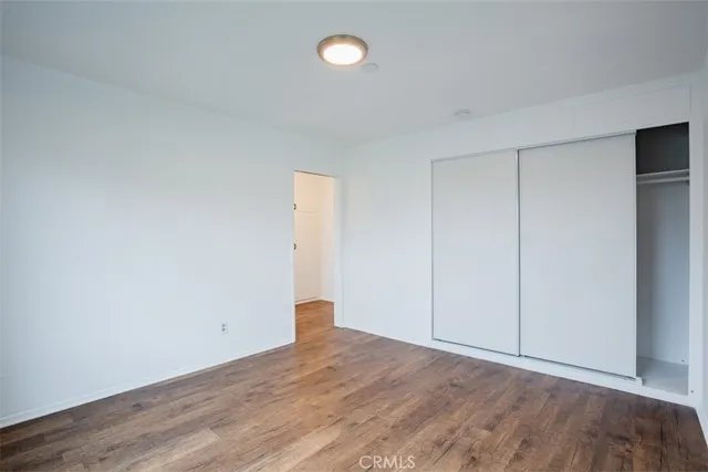 an empty room with wooden floor and fan
