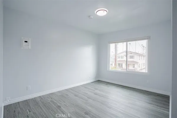 a view of an empty room with wooden floor and closet