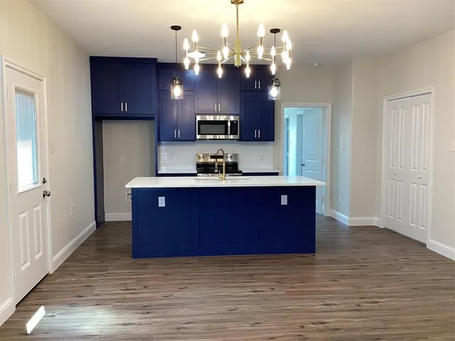 a kitchen with kitchen island granite countertop stainless steel appliances cabinets a sink and a counter top space