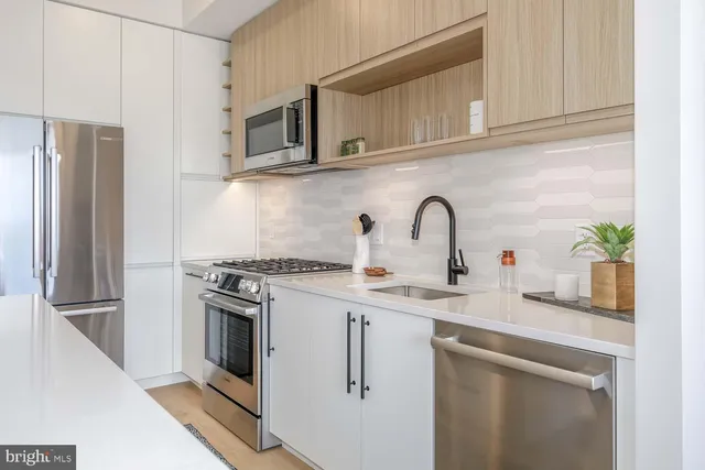 a kitchen with stainless steel appliances granite countertop a sink a stove a refrigerator and cabinets