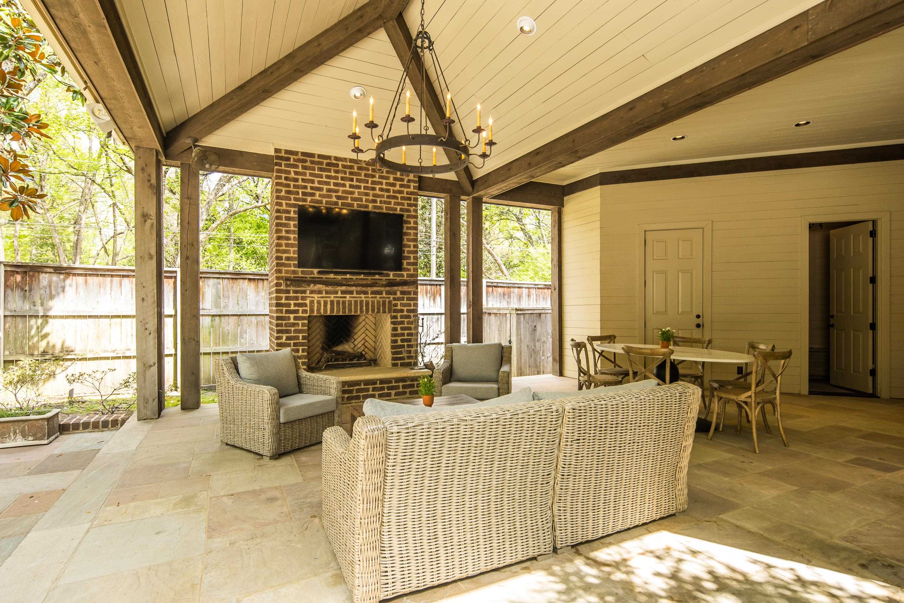 101 North Grove Park Road Memphis, TN 38117 - Photo 33 of 40 Living area with stone tile floors, an outdoor brick fireplace, suspended lighting, wood walls, and a wood ceiling with exposed beams
