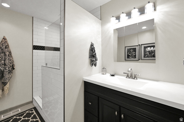 2314 Ridgewood Way Bountiful, UT 84010 - Photo 14 of 26 Glass-enclosed shower with subway tile and hexagon accent, complemented by a vanity with a white countertop and dark cabinetry, and a mirrored medicine cabinet