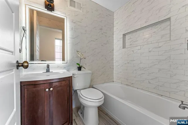 a bathroom with a granite countertop toilet a sink and a bathtub
