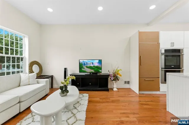 a living room with furniture a flat screen tv and a refrigerator
