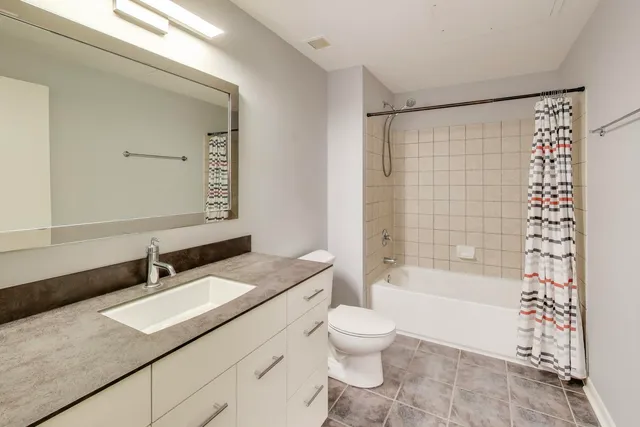 a bathroom with a granite countertop sink a toilet a mirror a vanity and shower