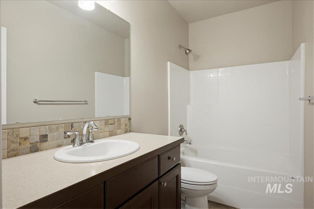 12460 West Azure Street Boise, ID 83713 - Photo 26 of 34 Bathroom featuring a dark wood-finish vanity with an integrated sink, a light-toned countertop, and a tiled backsplash