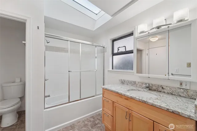 a bathroom with a granite countertop sink a toilet and a mirror