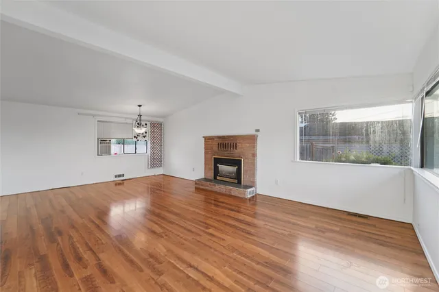 a view of empty room with wooden floor and fireplace