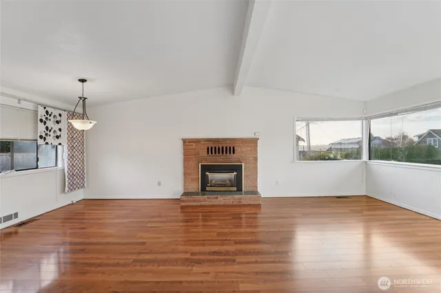 a view of empty room with wooden floor and fireplace