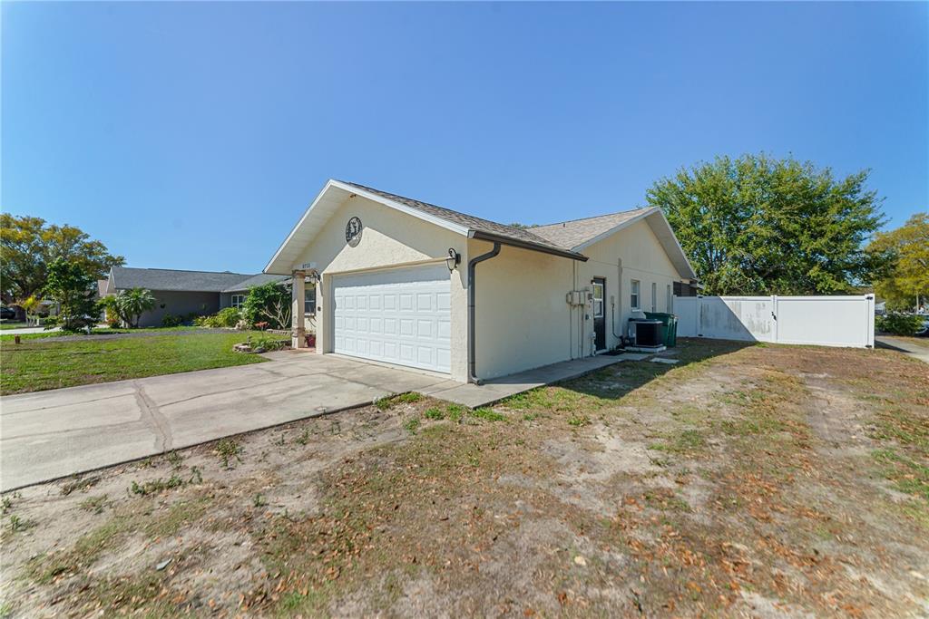 8715 Huntsman Lane Port Richey, FL 34668 - Photo 4 of 54 a view of a house with a yard and garage