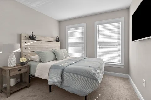 a bedroom with a bed and a flat tv screen on a dresser