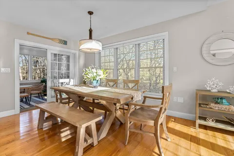a dining room with wooden floor a chandelier a wooden table and chairs