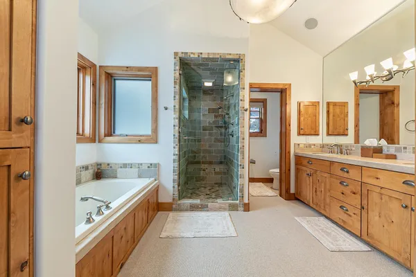 a bathroom with a granite countertop tub sink shower and mirror