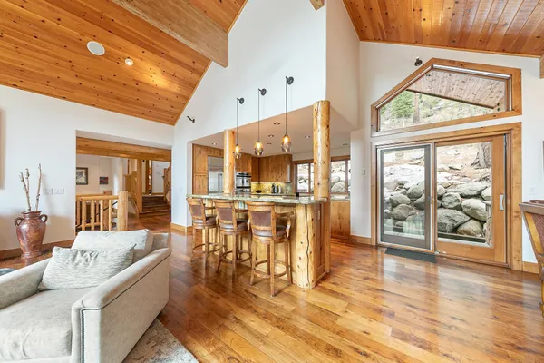 a dining hall with stainless steel appliances granite countertop a refrigerator a stove and white cabinets with wooden floor