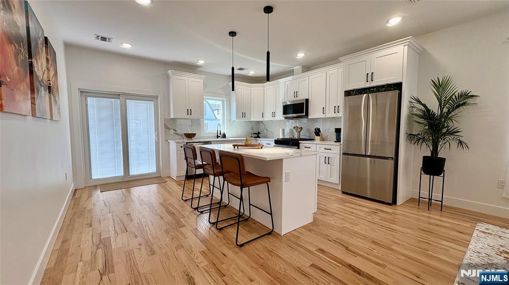 367 Devon Street, Unit 2 Kearny, NJ 07032 - Photo 12 of 30 a kitchen with stainless steel appliances a refrigerator a stove a sink dishwasher and a dining table with wooden floor