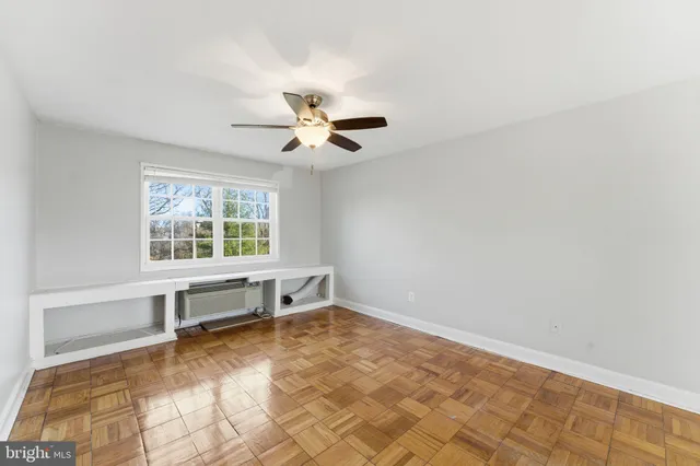 an empty room with windows and ceiling fan