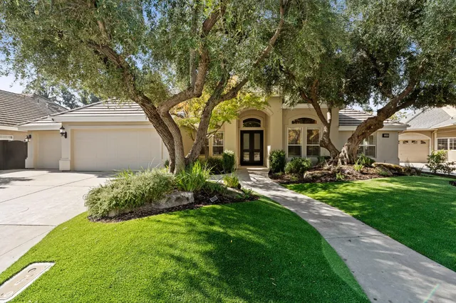 a front view of a house with a garden and trees