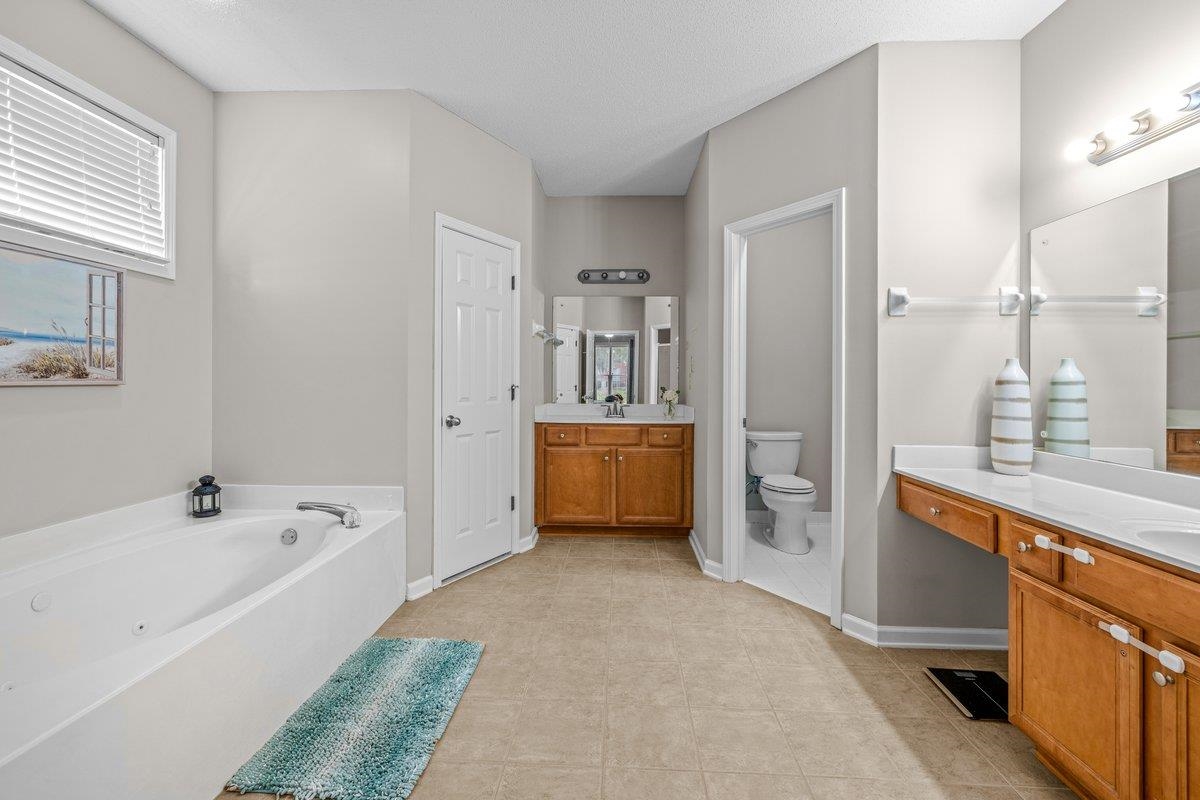 4840 Rainy Pass Road Collierville, TN 38017 - Photo 22 of 30 Bathroom featuring a built-in jetted tub, dual vanity with wood cabinetry, and a separate water closet