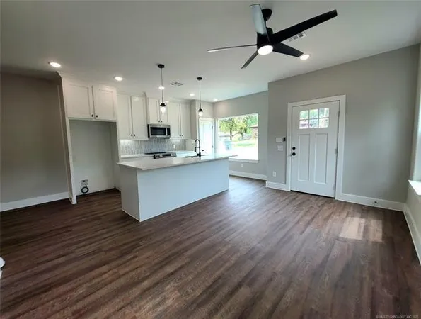 a large kitchen with cabinets wooden floor a large window and stainless steel appliances
