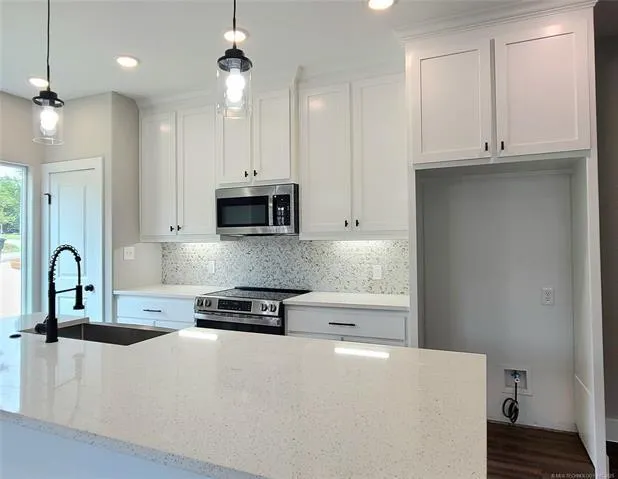 a kitchen with stainless steel appliances granite countertop a stove a sink and a white cabinets
