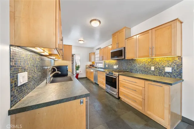 a kitchen with stainless steel appliances granite countertop a sink a stove and cabinets