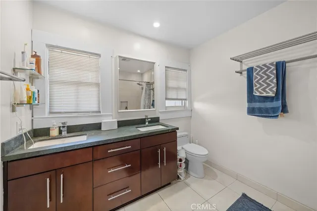 a bathroom with a granite countertop sink a toilet and a mirror
