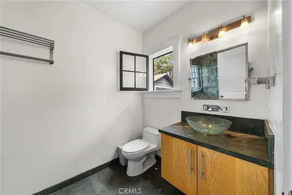 a bathroom with a granite countertop toilet sink and mirror