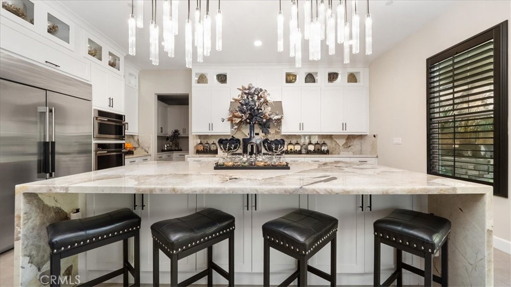 8798 JUSTIFY Drive Rancho Cucamonga, CA 91701 - Photo 5 of 26 a kitchen with stainless steel appliances kitchen island granite countertop a table chairs sink and cabinets