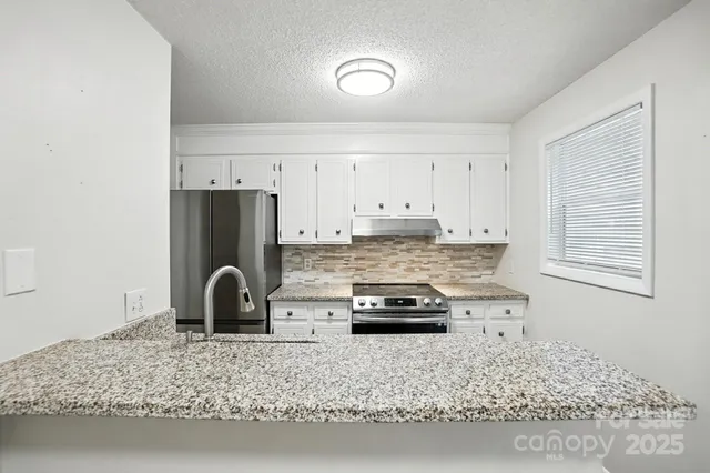 a kitchen with kitchen island granite countertop a sink stove and refrigerator