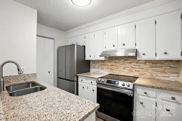a kitchen with granite countertop a stove sink and refrigerator