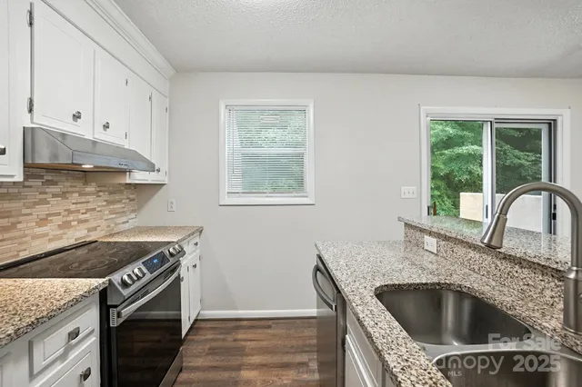 a kitchen with granite countertop a sink stove and refrigerator