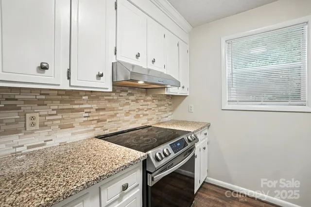 a kitchen with granite countertop white cabinets and a stove