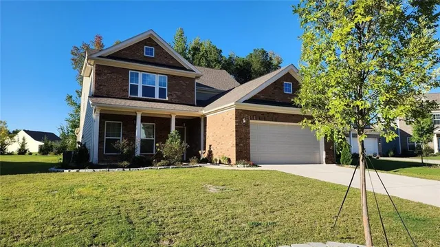 a front view of a house with a yard and trees