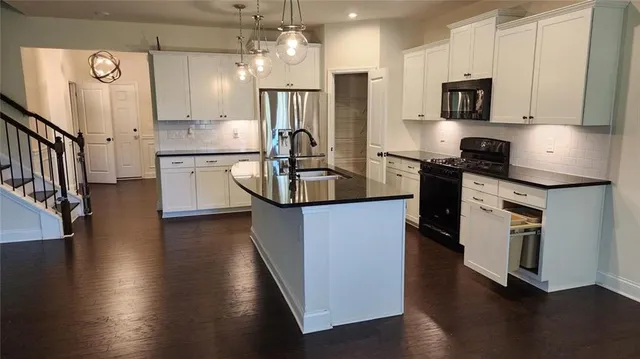 a kitchen with stainless steel appliances granite countertop a refrigerator a stove a sink and a microwave