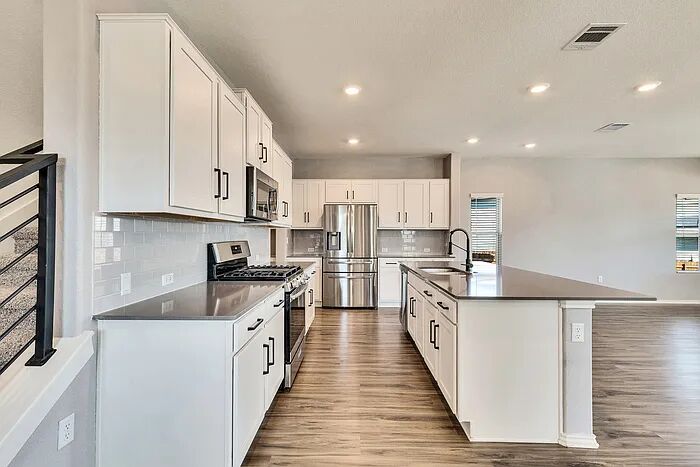 10403 Bramble Berry Drive Austin, TX 78748 - Photo 4 of 21 a large kitchen with stainless steel appliances granite countertop a lot of counter space and wooden floors