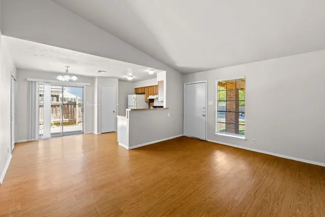 a view of an empty room with window and wooden floor