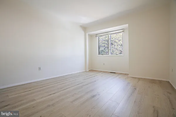 an empty room with wooden floor and window