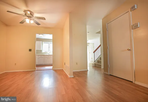 an empty room with wooden floor cabinet and windows
